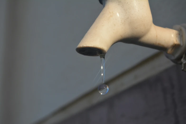 a close up view of a water drop being blown by the faucet