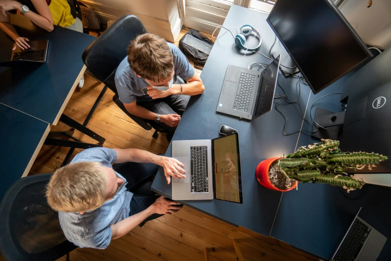 three people work at tables in a bright office