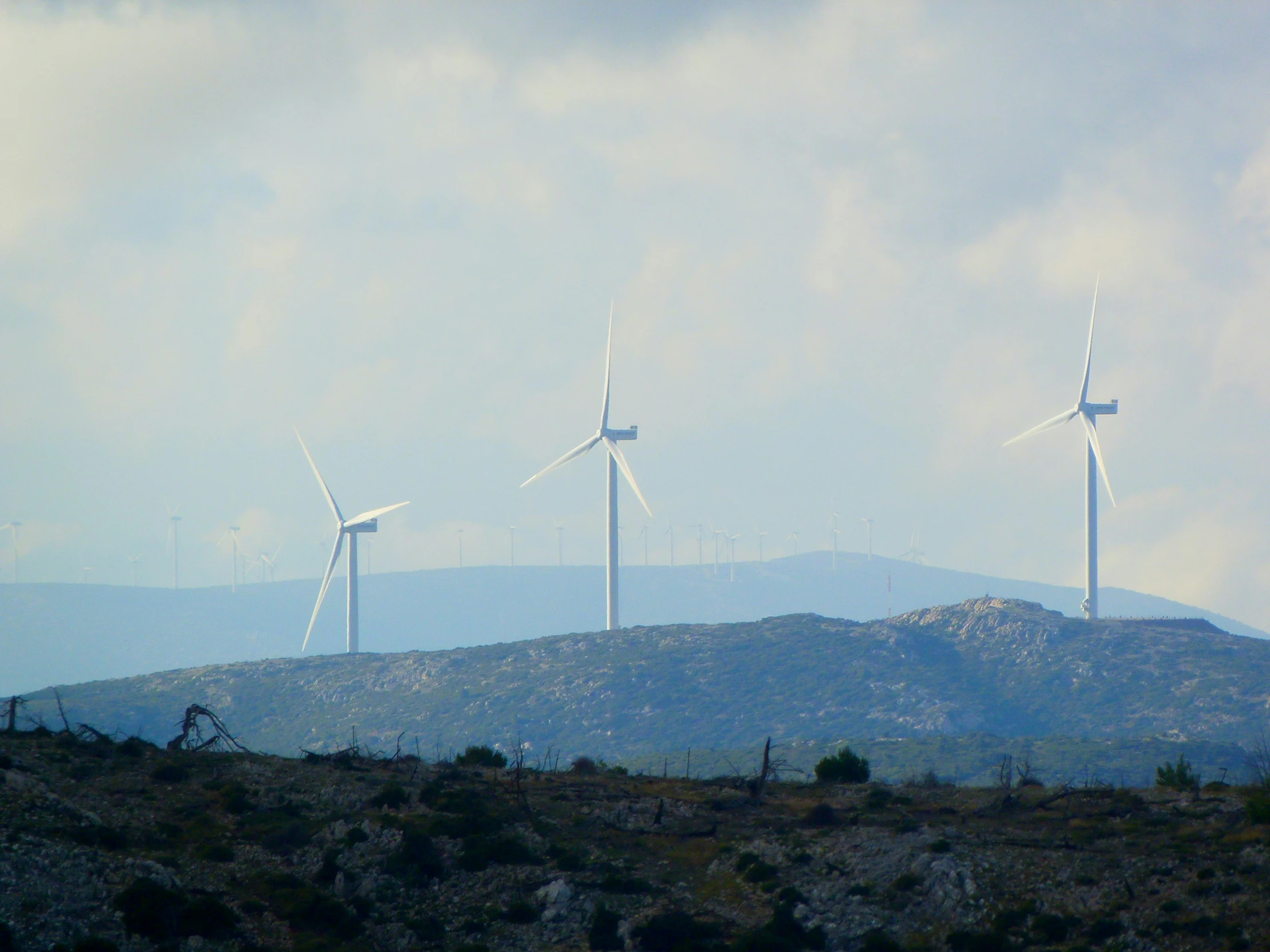 a group of windmills on the horizon, surrounded by hills