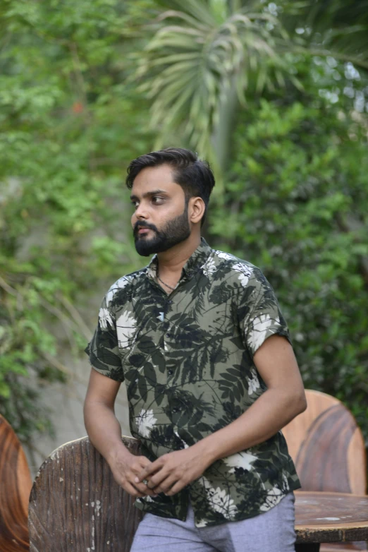 man with flowered shirt standing in front of wooden bench