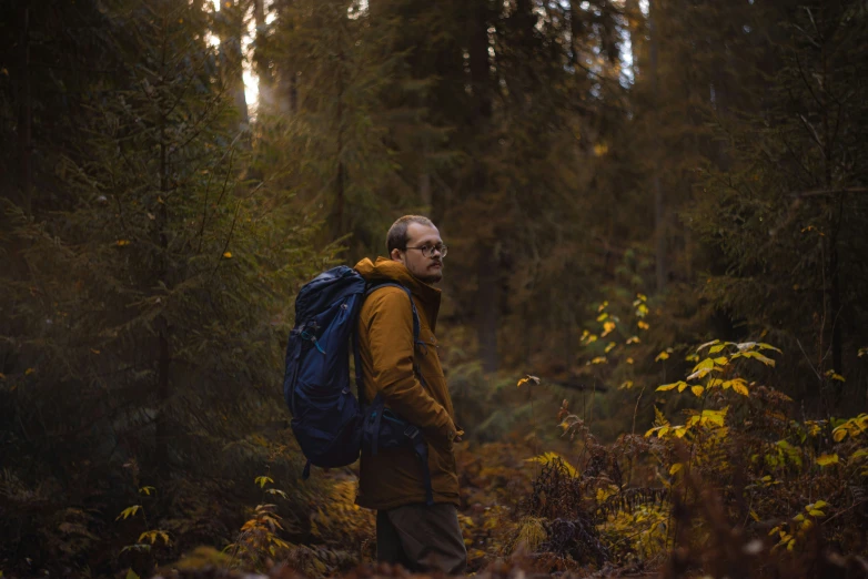 a man is carrying a backpack through the woods