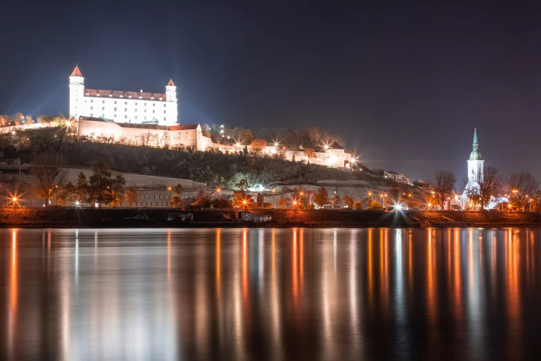 a castle lit up on a hill over looking water
