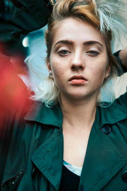 a woman with a green coat is shown with her hair blowing in the wind