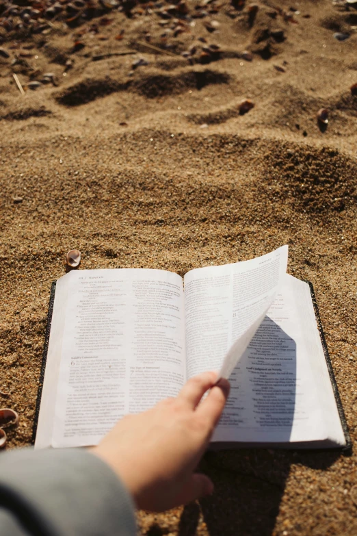 person holding open book while lying on the ground