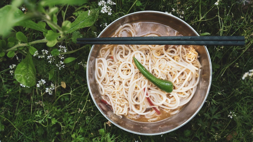 noodles and vegetables sitting in a bowl next to chop sticks