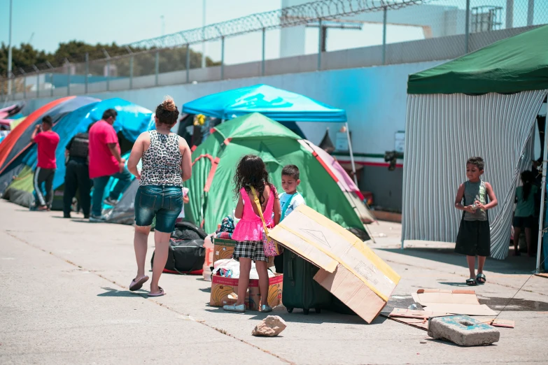 many people standing near tents, one girl has her luggage