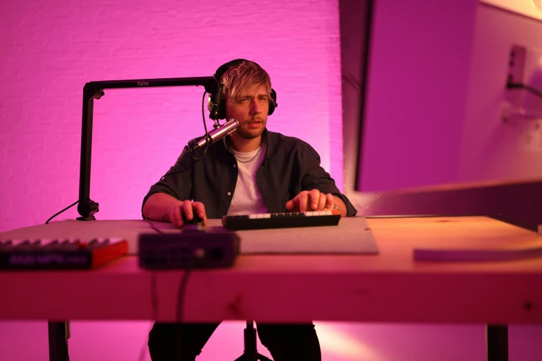 a young man sitting at a computer desk with headphones on