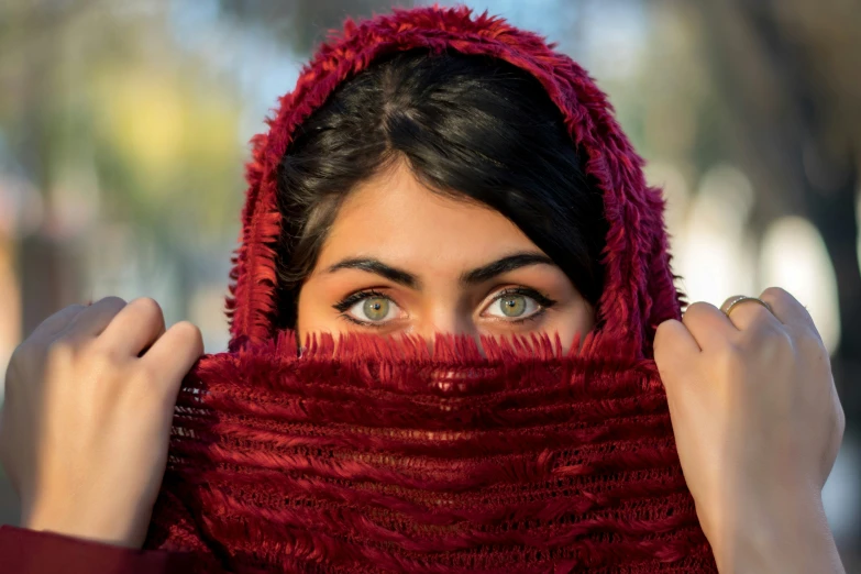 a woman is looking over her red scarf