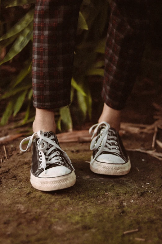 a person standing on a piece of grass wearing tennis shoes