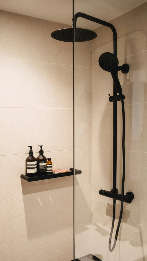 shower head with black shower faucet in white tiled bathroom