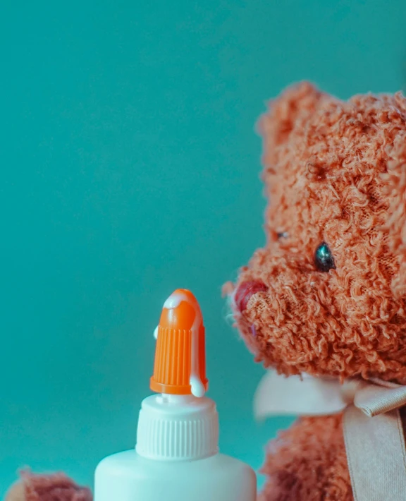 an orange and white teddy bear holding a bottle