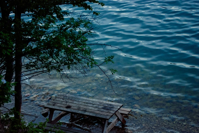 a bench is seen on the shore in the evening