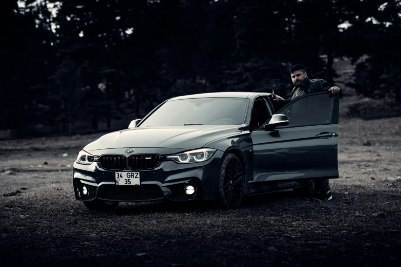 a man sitting on the trunk of a silver car