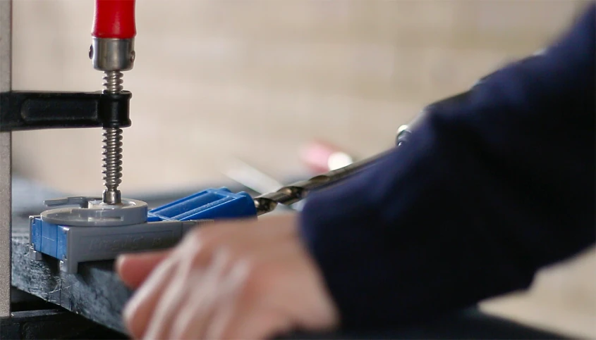 a machine with drill holes and two red screws