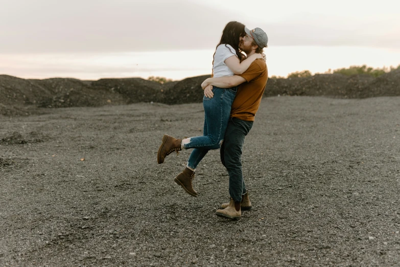 a couple standing in the dirt with one holding the other up