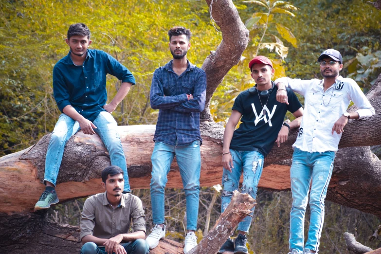 a group of men sitting on a tree nch in the woods