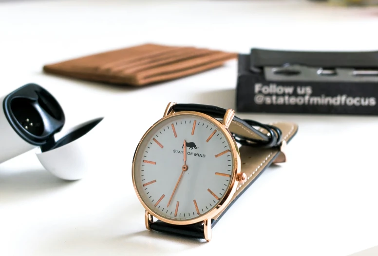 a rose gold watch sits on a black leather strap