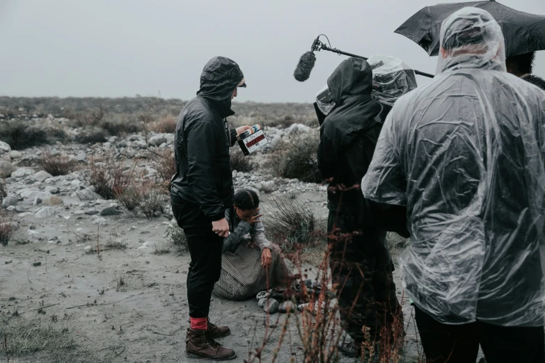 group of people in rain gear and hoods, all looking at soing