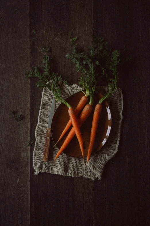 there is three carrots on a plate and two knives