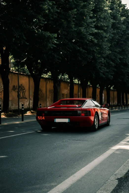 a red sports car is on the side of a road near some trees