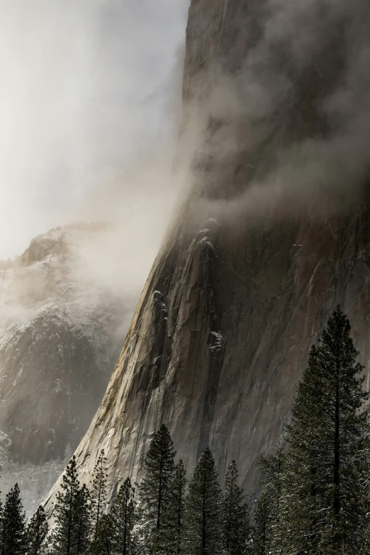 a mountain with fog pouring in the top