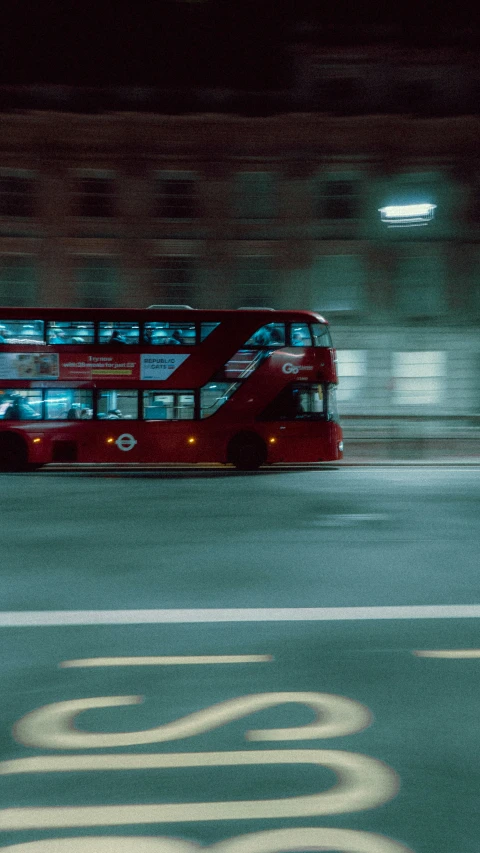 a red double decker bus driving down a street