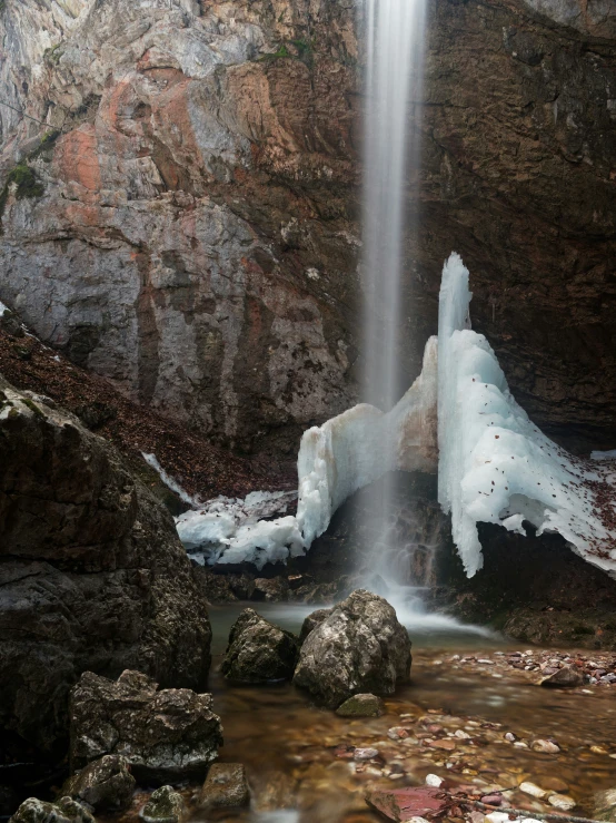 some ice blocks on the rocks by a waterfall