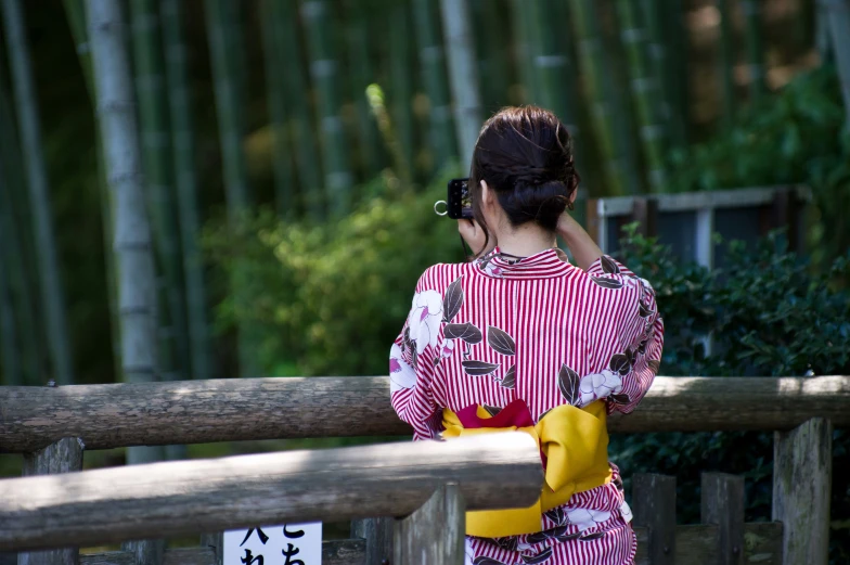 a woman is on a cell phone in front of a bamboo tree