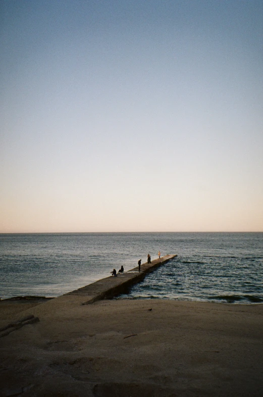 people are sitting on the pier overlooking the ocean