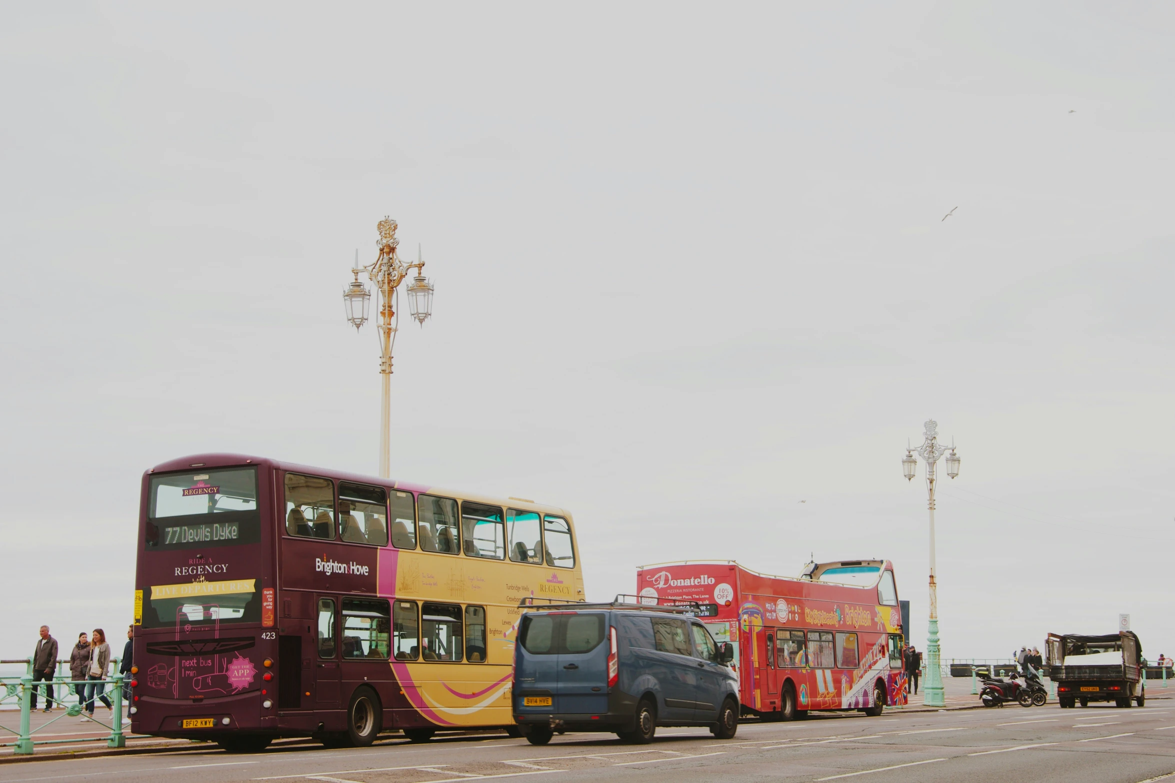 the multi - colored bus is parked along the curb of the side of the street