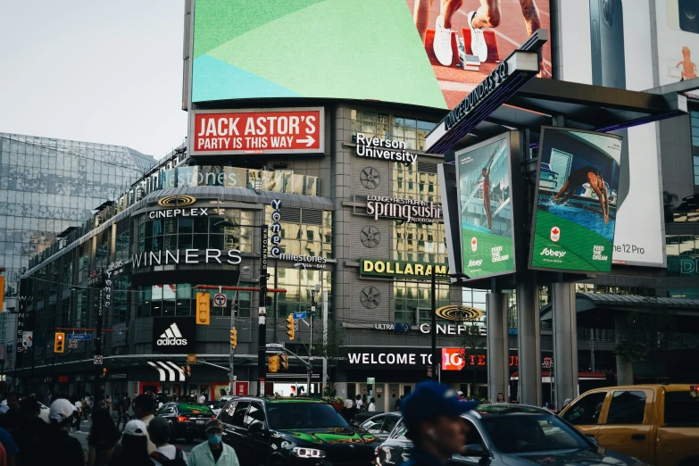 a city street with various billboards and people walking by