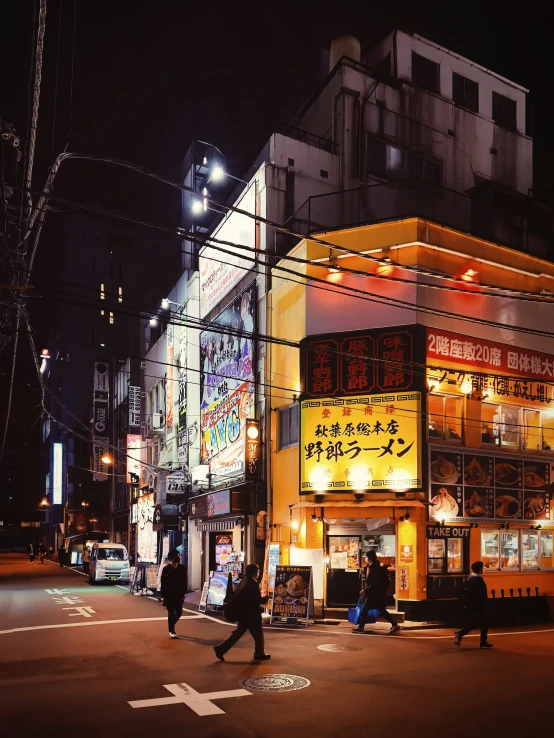 a street scene with several pedestrians and a store at night