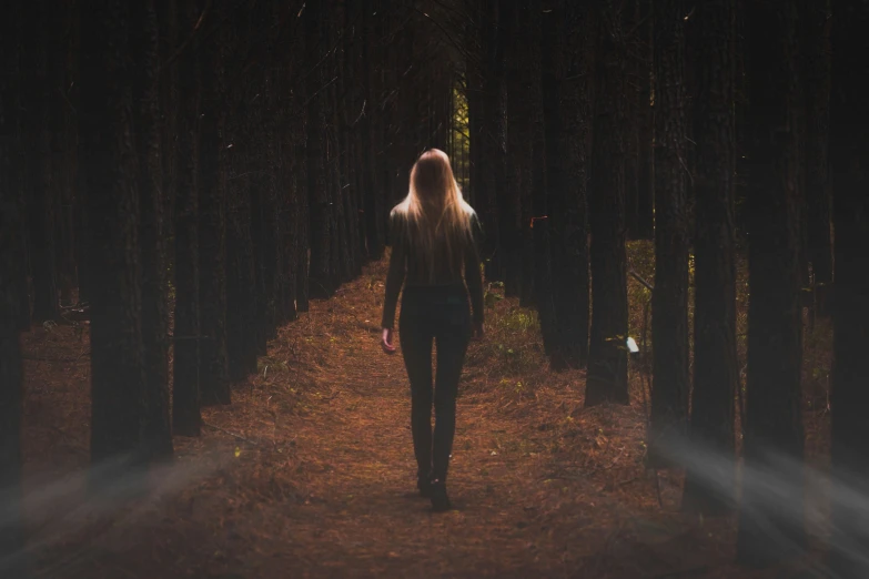 a woman walks through the dark forest