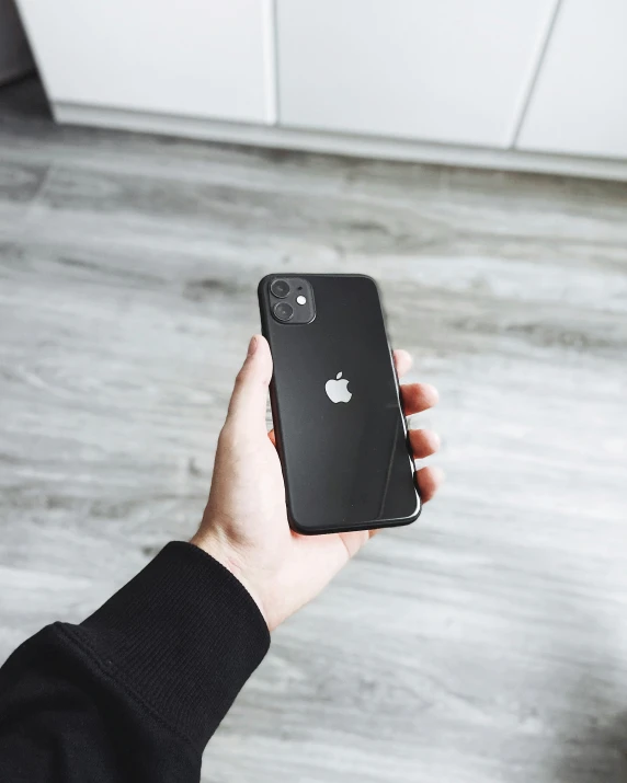 a person is holding up a black apple phone