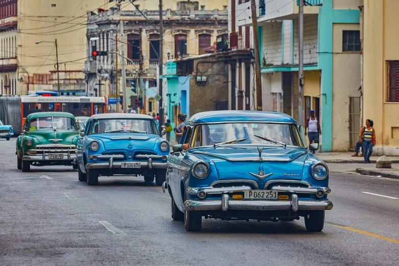 three old time car lined up in the street