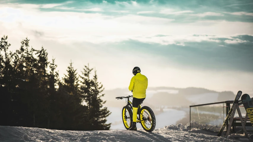 a man riding on the back of a bike down a snow covered hillside