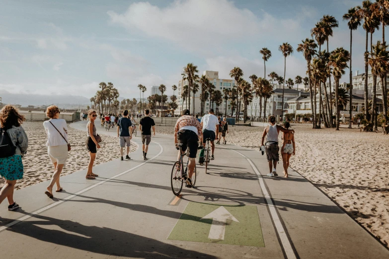 a group of people on bicycles and walking on the beach