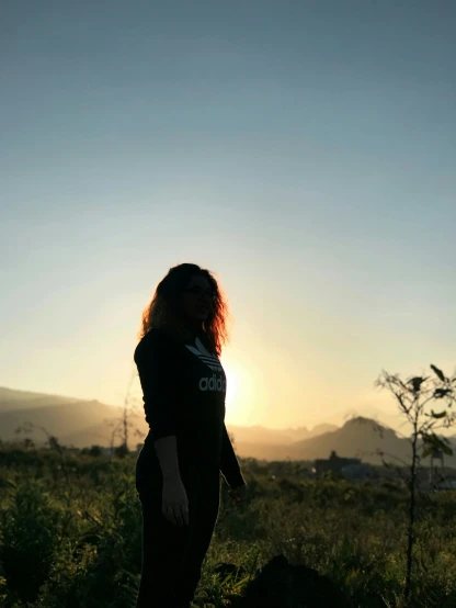 a person standing in a field with a sunset behind them