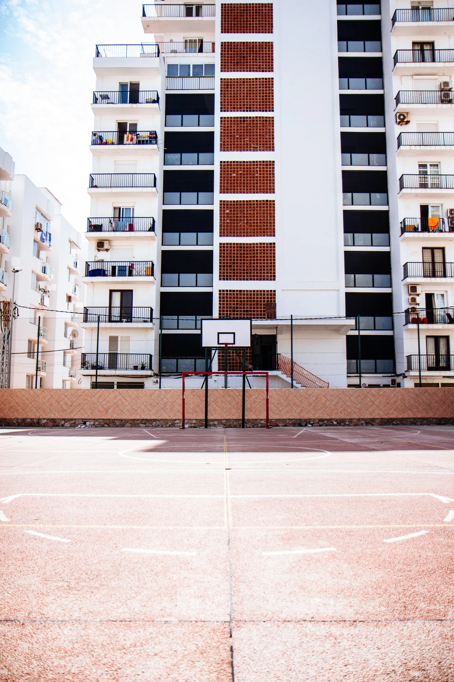 a tall building behind a basketball court with a hoop in front