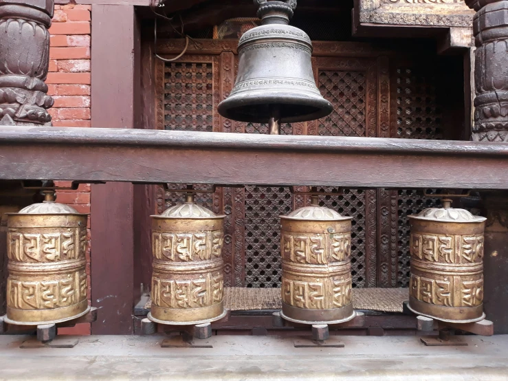 four bells hang from a wooden stand by the entrance