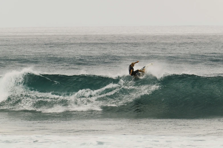 a surfer in wetsuit on wave in open ocean