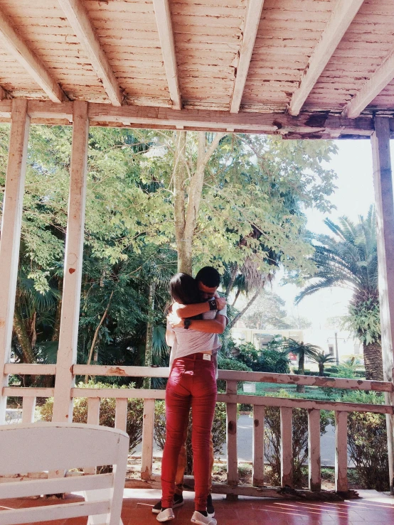 two young people hug each other on a porch