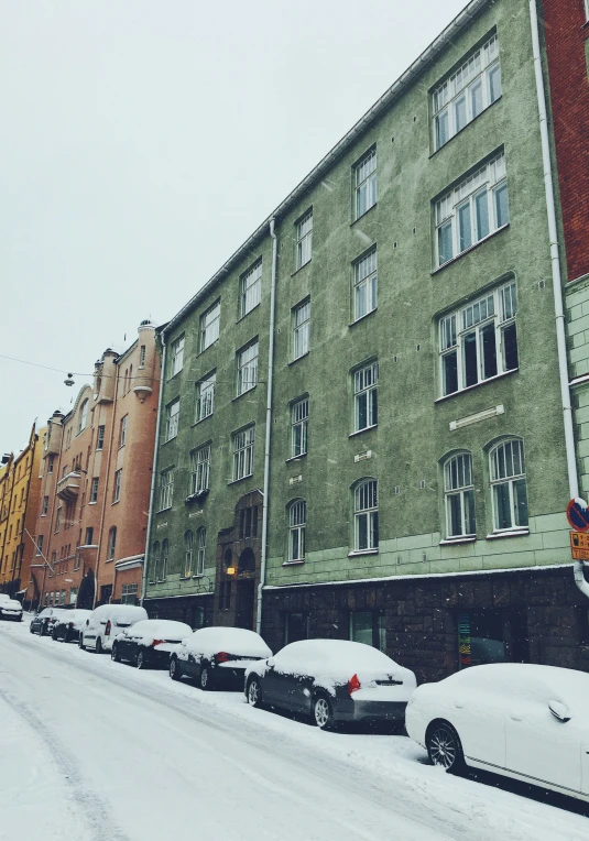 an intersection is covered in snow with several cars parked on the curb