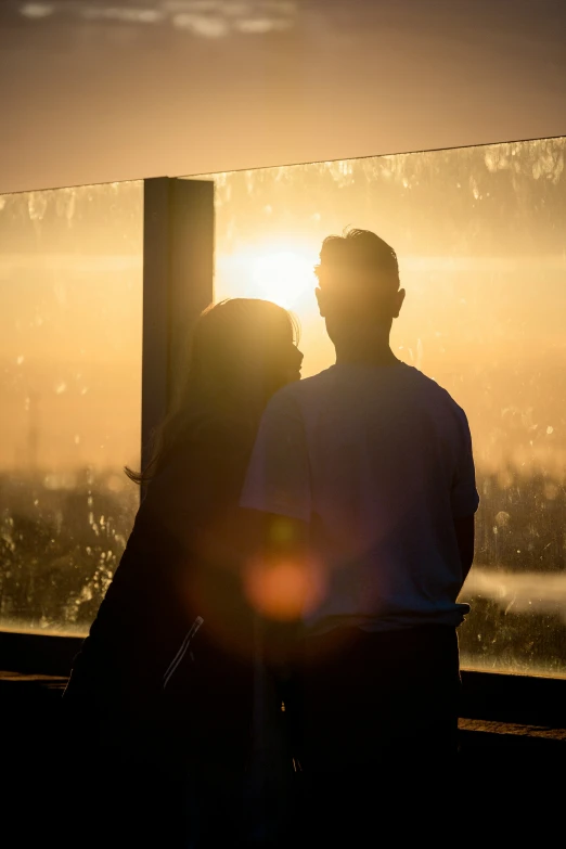 a couple standing in front of a fence