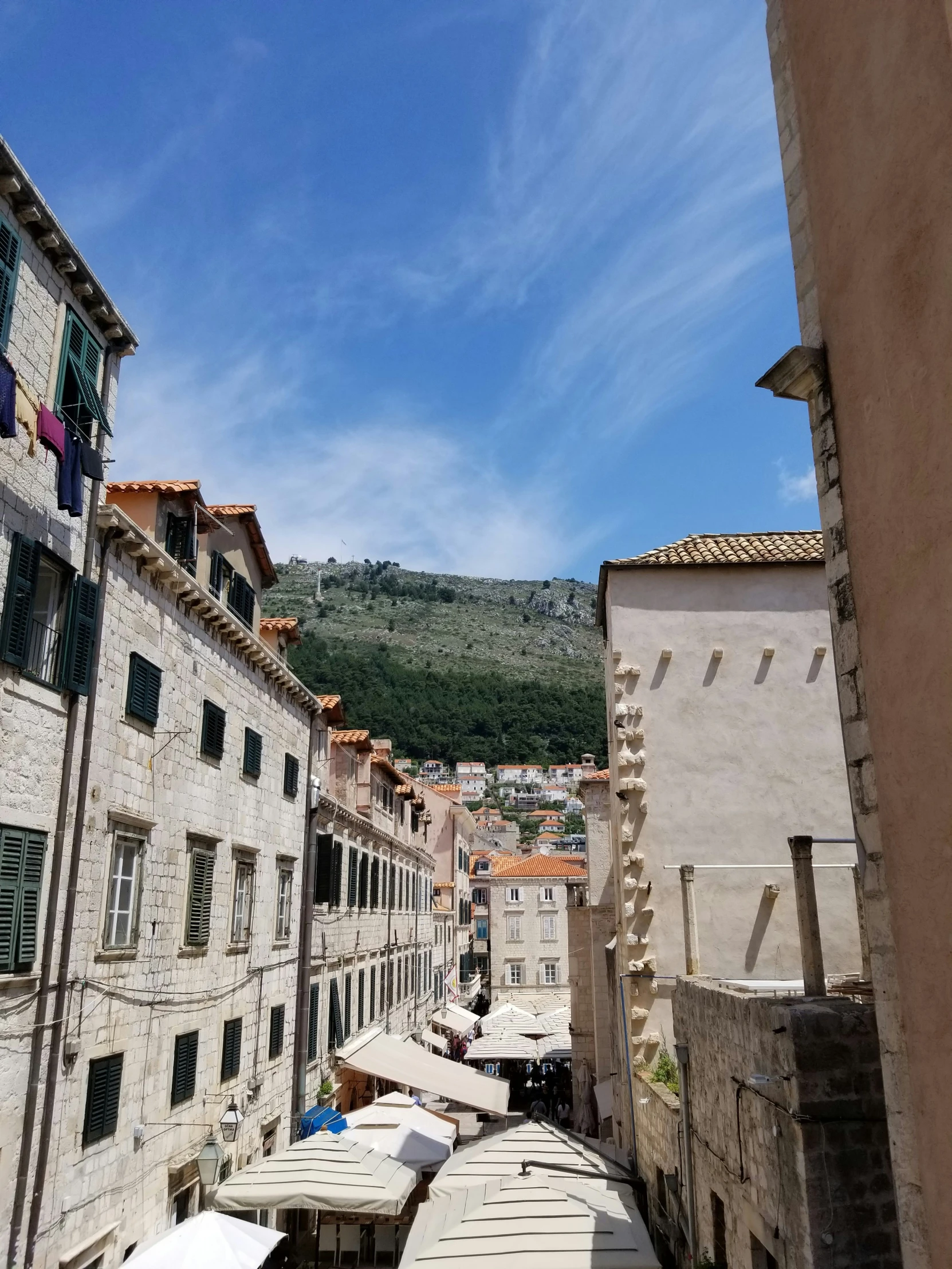 the view of an alley way with umbrellas and buildings