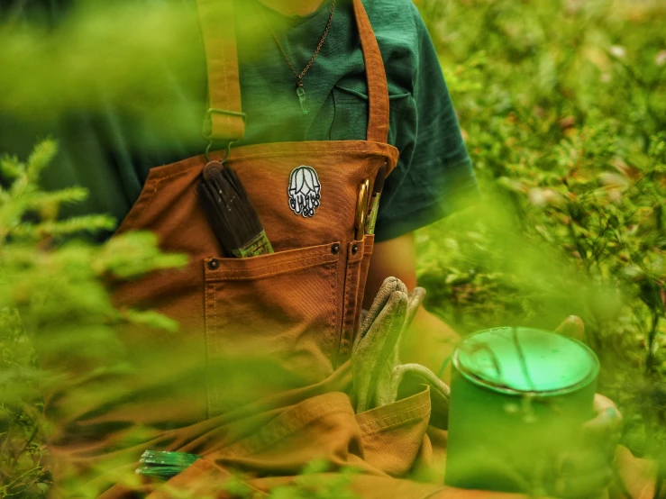 someone in the grass holding a bag next to a pot