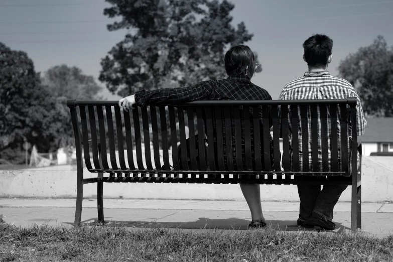 two people sitting on top of a wooden bench