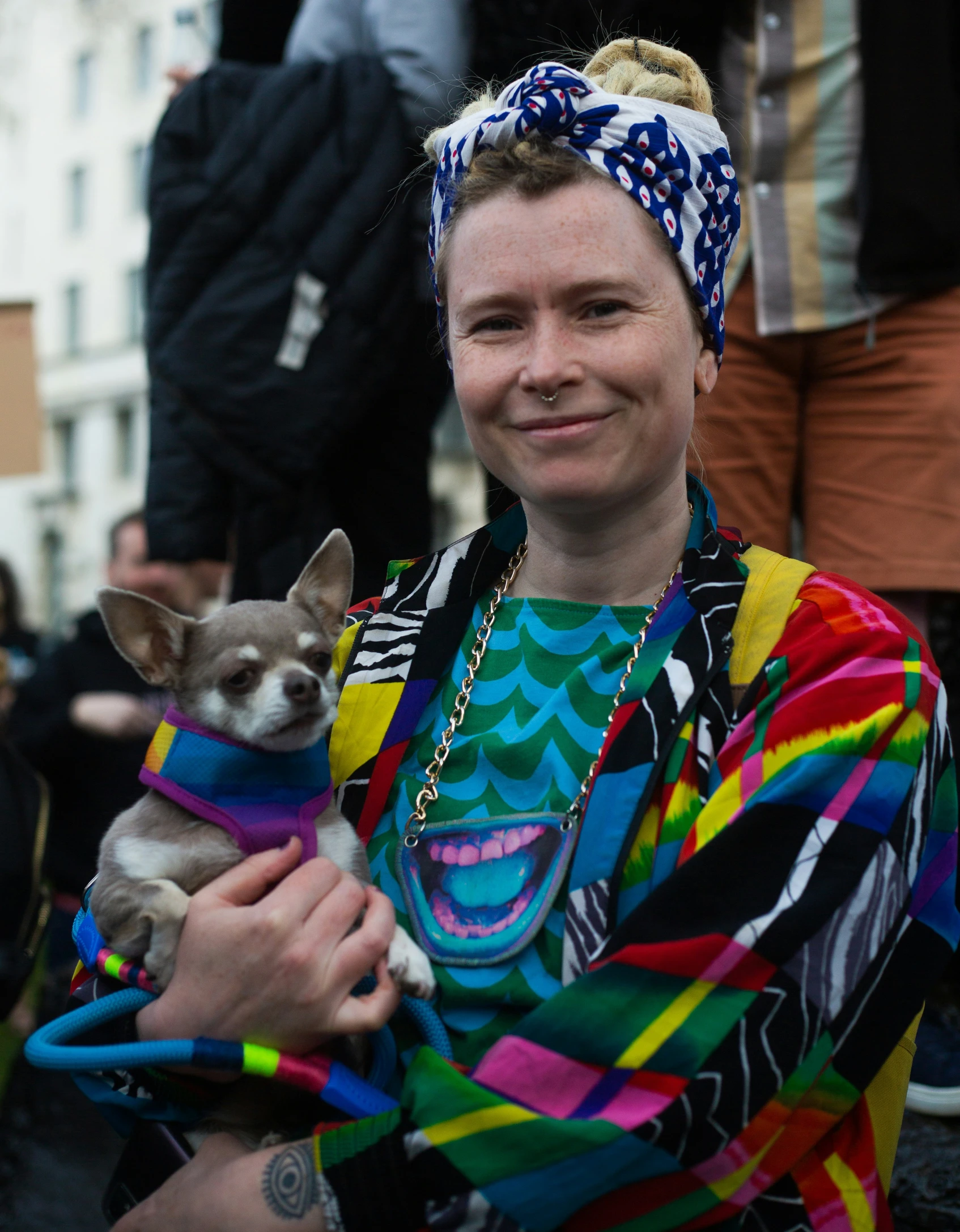 the man has a small dog wearing a colorful shirt