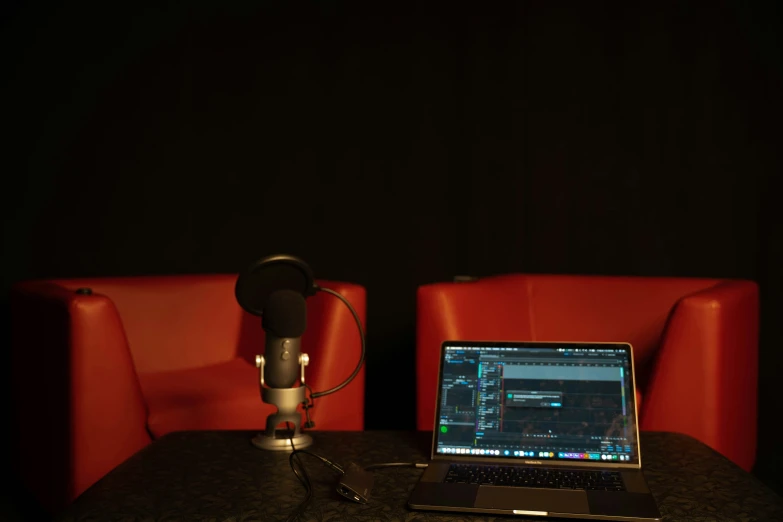 a laptop computer sitting on a table in front of a microphone