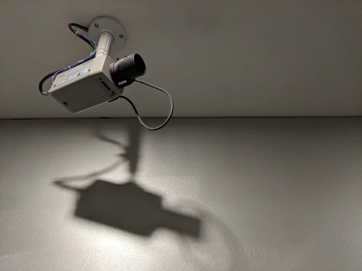 an old phone with a camera attached to it and shadow on a wall